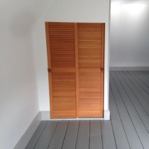  set of wooen doors in an empty room with a finished wooden fllor