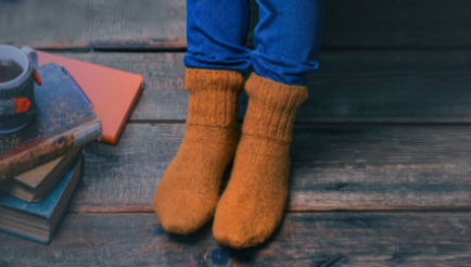 A paid of legs on a dark wooden floor, wearing cosy warm socks