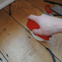 Draughtex being fitted into a flooerboard gap using the applicator