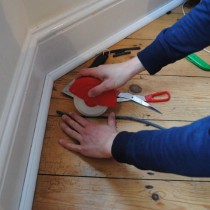 Draughtex being fitted into a flooerboard gap using the applicator