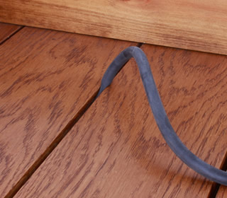 DraughtEx being stretched into a narrow gap between two floorboards